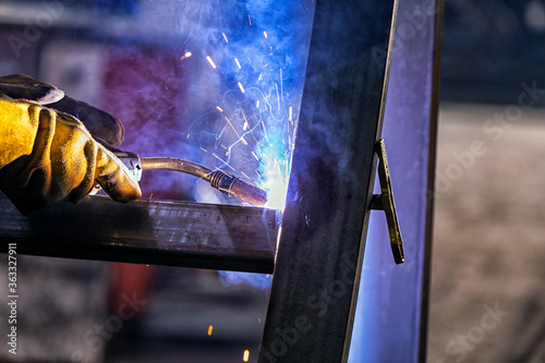 The welder is welding a structural steel with gas metal arc welding ( GMAW ) in the workshop. photo