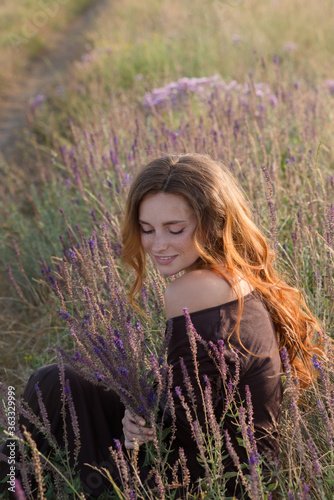 beautiful young girl walks in a summer field at sunset