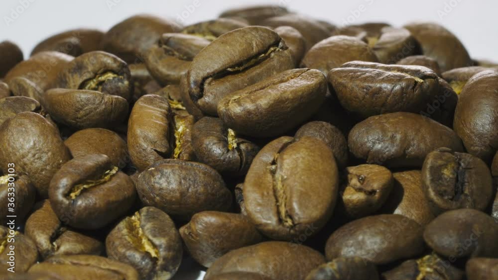 Dark Coffee beans rotating. Close up of roasted coffee beans on white background. Shallow depth of field Dark Coffee beans rotating. Close up of roasted coffee beans on white background. Shallow depth of field