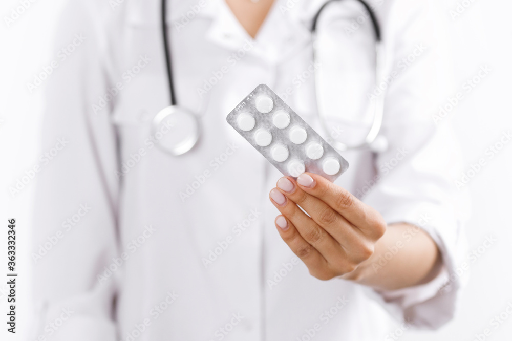 Close-up of male doctor's hand holding pills for his patient. Young Caucasian men medic wearing professional uniform and stethoscope. Close-up of male doctor's hand holding pills for his patient. Young Caucasian men medic wearing professional uniform and stethoscope.