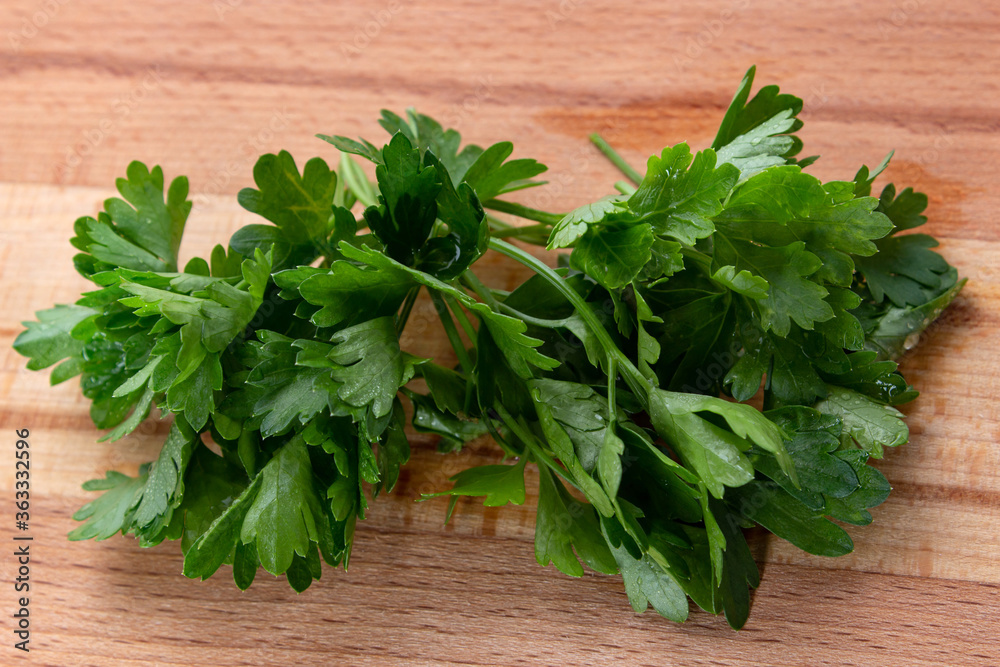 Parsley with water drops on wooden cutting board Parsley with water drops on wooden cutting board