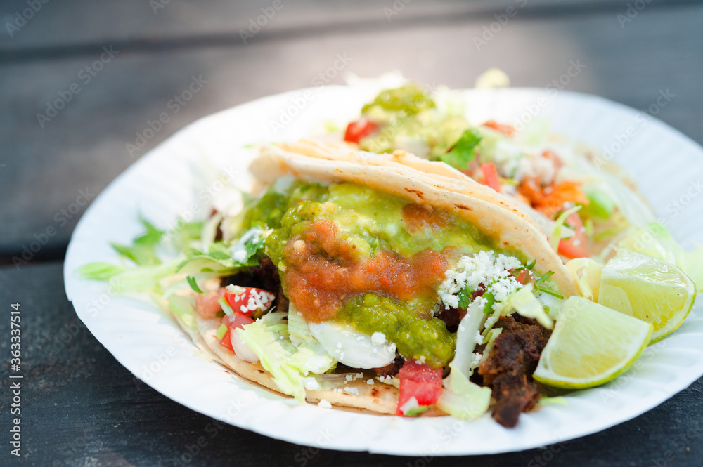 vegetarian refried bean tacos with lettuce and tomato drizzled with green tomatillo sauce and red salsa with lime wedge vegetarian refried bean tacos with lettuce and tomato drizzled with green tomatillo sauce and red salsa with lime wedge
