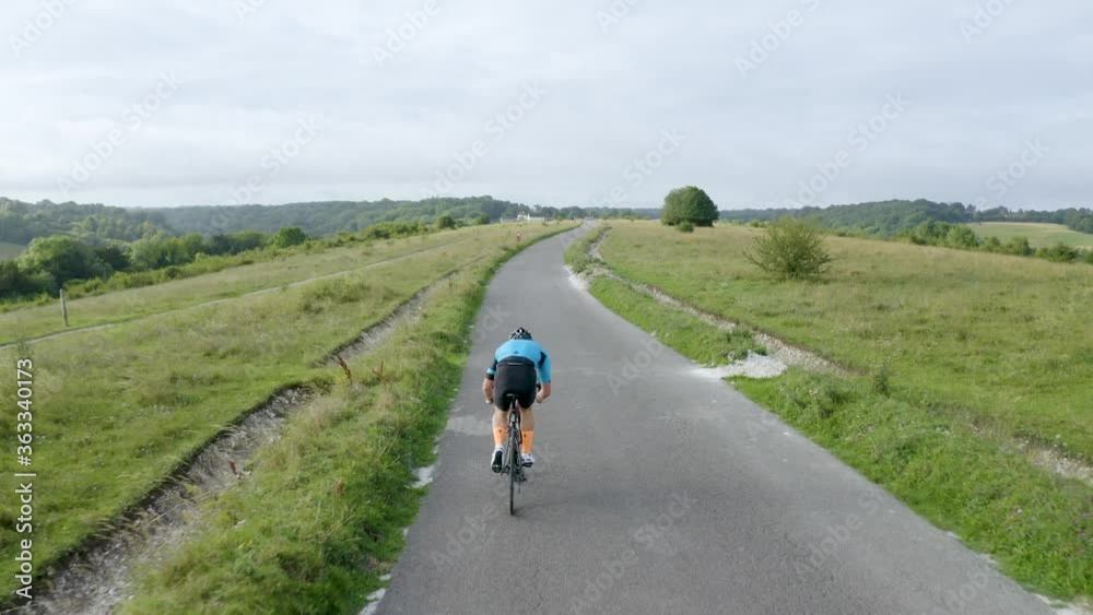 Drone tracking shot of a cyclist travelling fast along a British country road Drone tracking shot of a cyclist travelling fast along a British country road