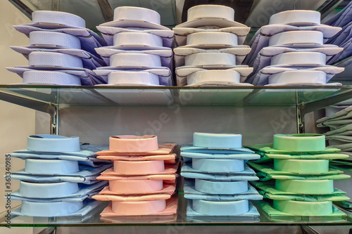 Folded mens shirts in a store. Shelves with a lot of colorful shirts neatly folded in the store clothes and business suits.