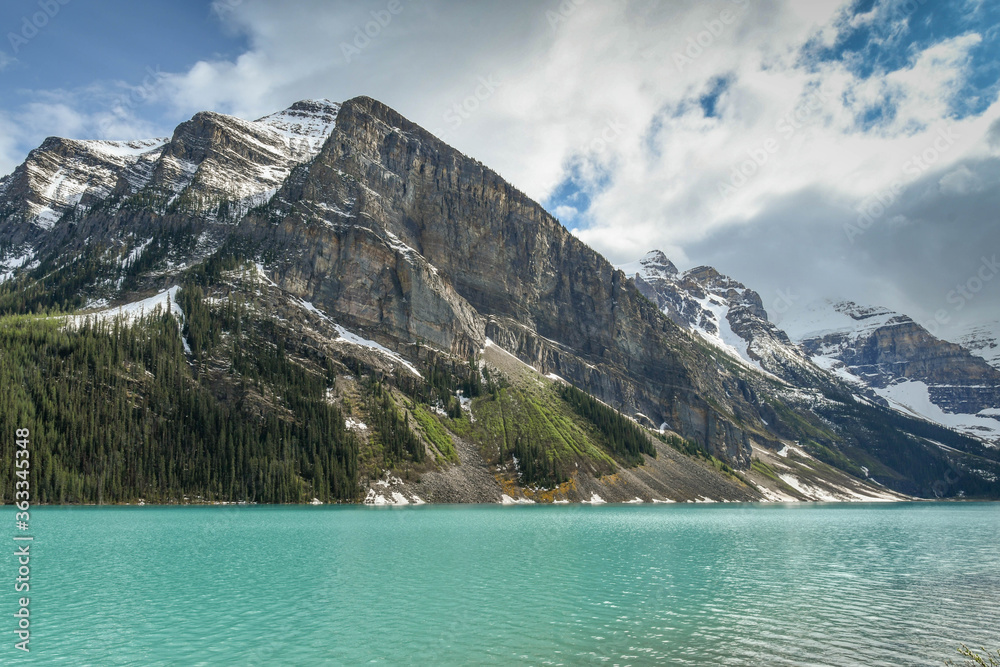 LAKE LOUISE, AB, CANADA - JUNE 2018: Emerald waters of Lake Louise in Banff National Park, surounded by snow capped mountains.