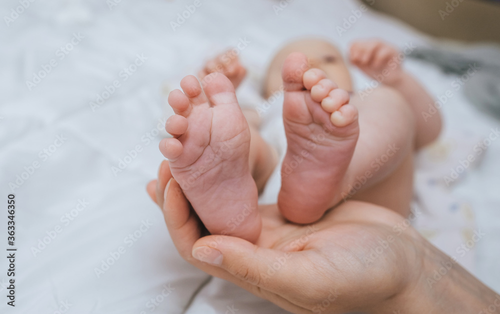 A loving, caring mother holds in her palm the legs of a small sleeping baby close-up. Woman's happiness. Photography, concept. A loving, caring mother holds in her palm the legs of a small sleeping baby close-up. Woman's happiness. Photography, concept.