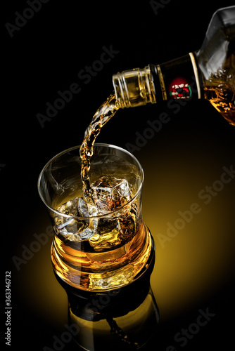 Whiskey with ice from a bottle Alcohol drink whiskey yellow ice bar drunk background black success holiday joy cold delicious pouring booze алкоголь напиток виски желтый лед бар пьяный фон черный 