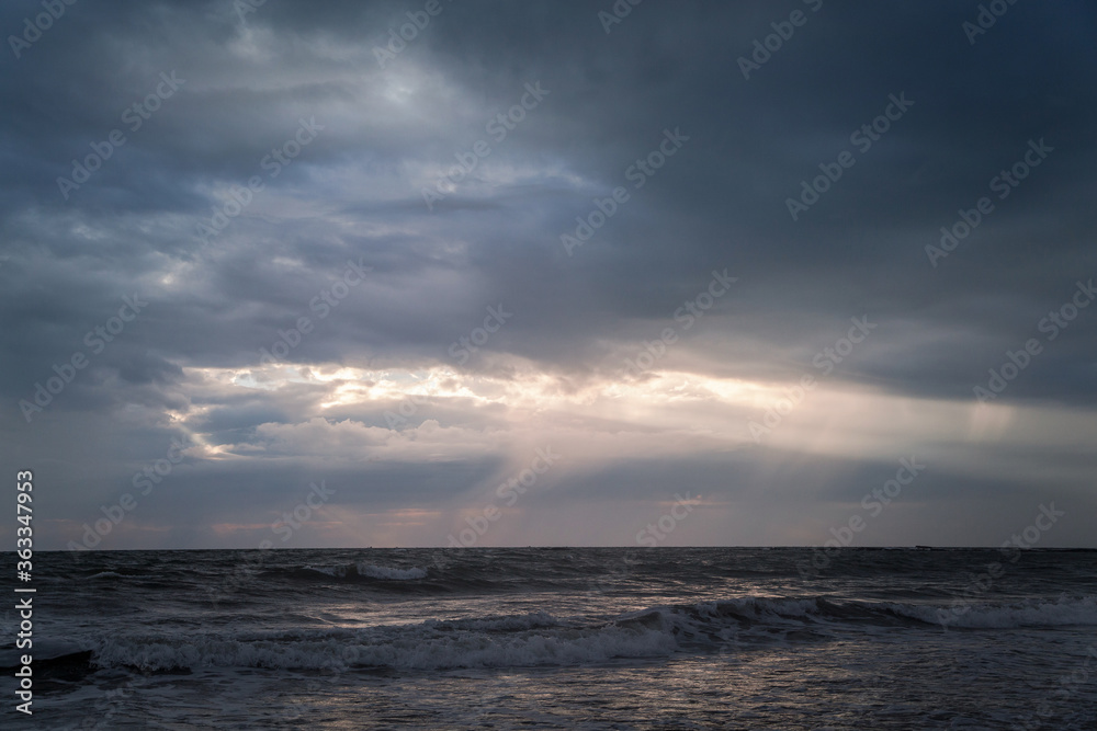 Beautiful evening sky with sun rays shining through the clouds over the Arabian Sea