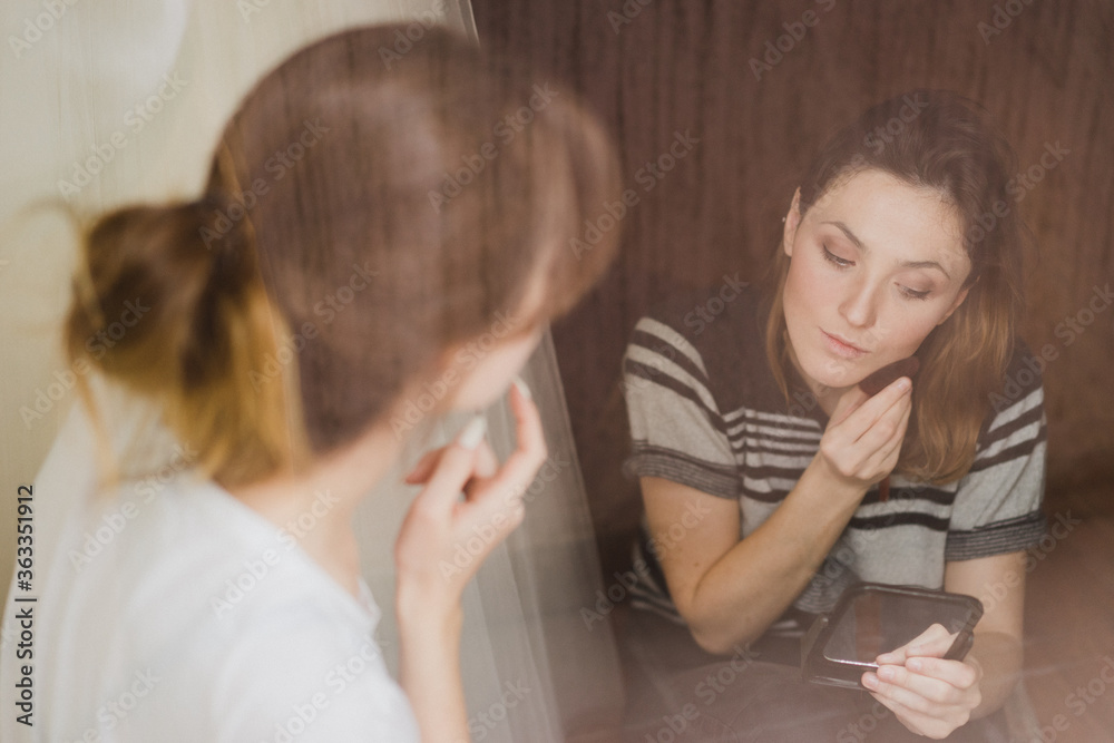 Beautiful modern caucasian woman doing make-up by herself looking at the mirror. Beautiful modern caucasian woman doing make-up by herself looking at the mirror.