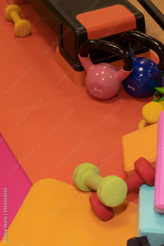 Set composition of various bright sports equipment. Kettlebells, fitness bands, cubes, rugs, dumbbells, barbell, step platform. Sport concept. High quality photo Set composition of various bright sports equipment. Kettlebells, fitness bands, cubes, rugs, dumbbells, barbell, step platform. Sport concept. High quality photo
