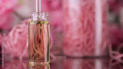 Blend of essential oils closeup. Making some aroma liquids, perfume. Drops falling from pippet to little glass bottle. Slowmotion. Liquid ingredients, body care production, cosmetology. photo