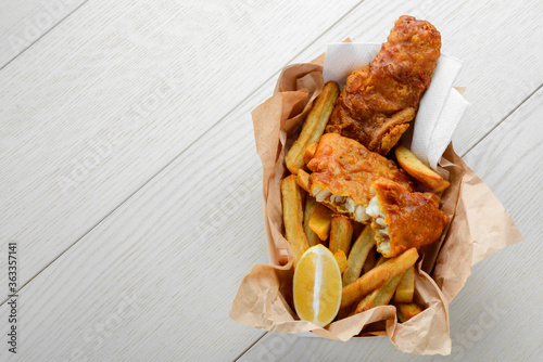 Batter cod and French fries with lemon in paper wrapper