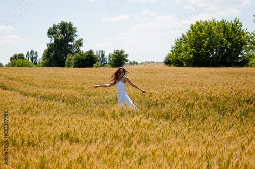 Bohemian style of clothing. girl dancing in a field in a beautiful white dress at sunset. beautiful carefree woman has windy hair. run away bride. happy girl feel free in rye field. wheat valley walk