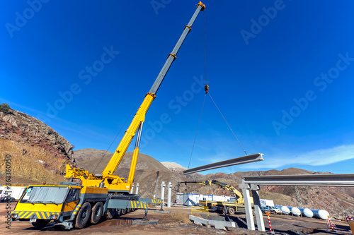 The big crane is lifting a concrete block for pipe bridge in the construction site.