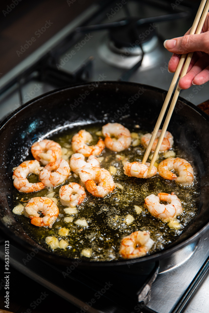 Process of frying giant red shrimps with garlic on olive oil on pan. Process of frying giant red shrimps with garlic on olive oil on pan.