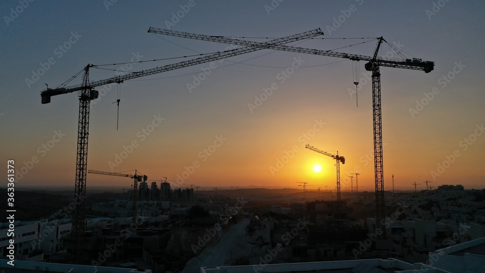 Cranes silhouette at construction site on beautiful sunset.
Modiin city, israel, july,2020