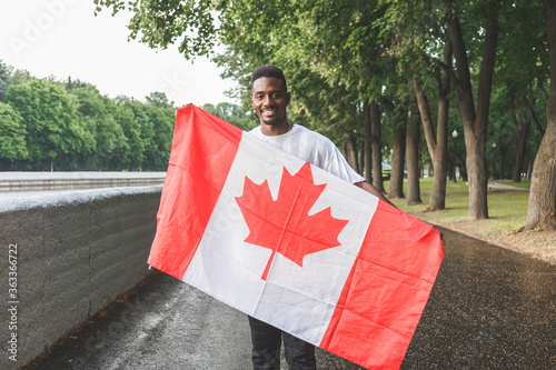Fotografie Handsome Afro American man with Canadian flag smiling at camera, standing outdoors