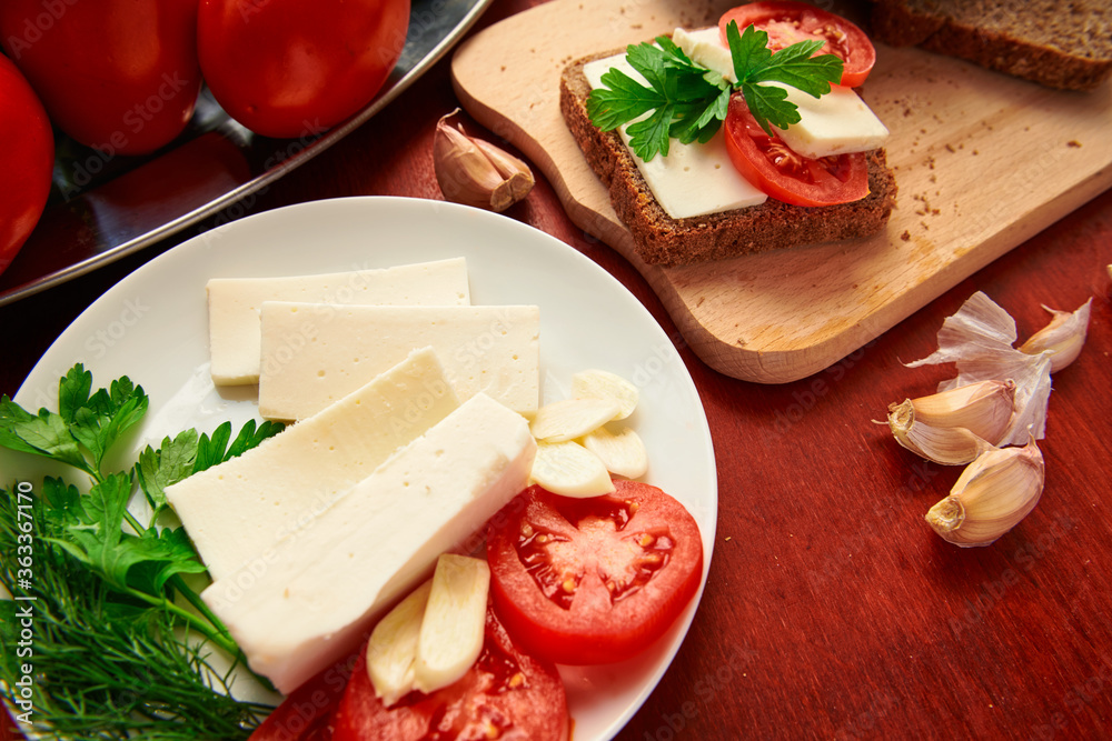 healthy food - fresh bread and feta cheese on a wooden background, tomatoes, greens and vegetables