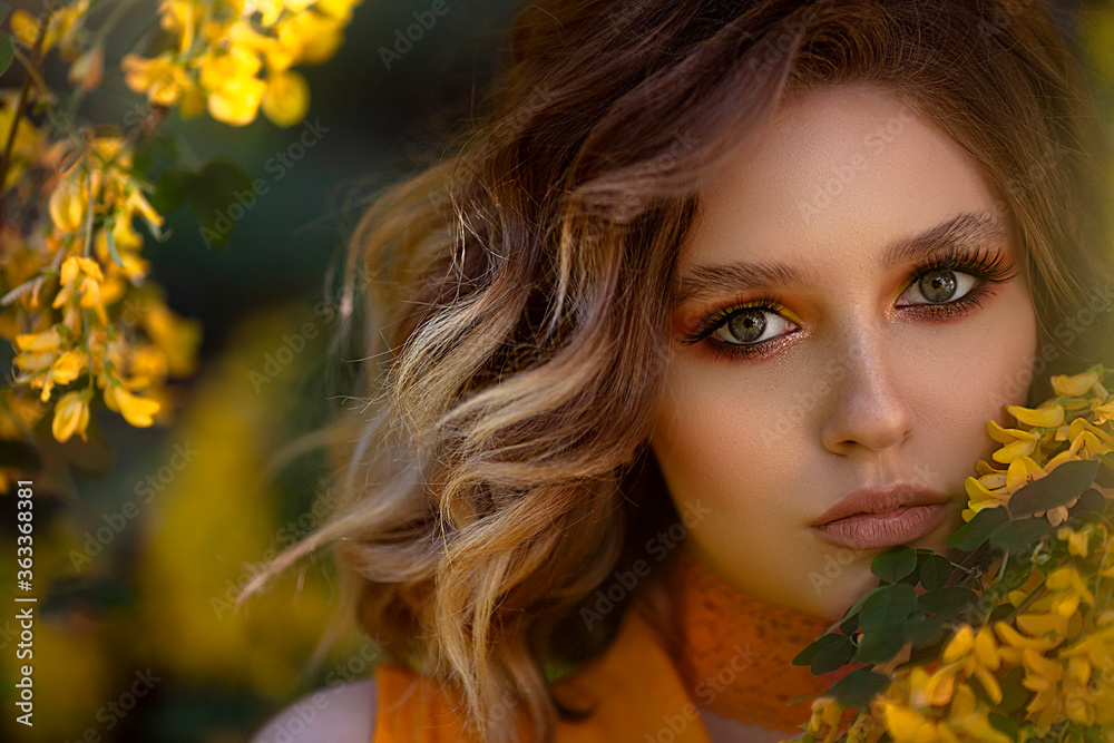Portrait of a Pretty sensual woman on a background of a yellow blossom tree. Summer time, summer colors.