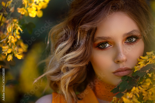 Portrait of a Pretty sensual woman on a background of a yellow blossom tree. Summer time, summer colors. © moredix