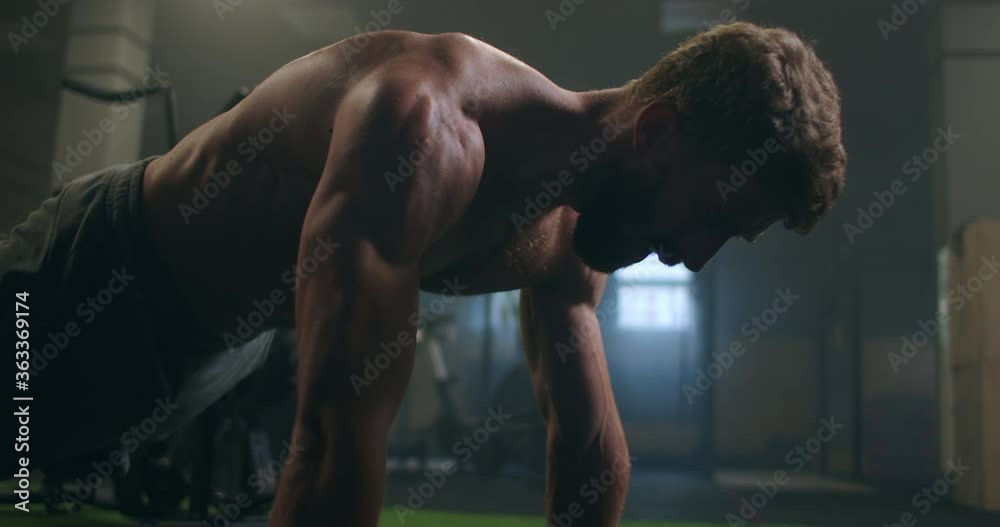 Man doing push ups in a gym. Exhaling and inhaling after push-ups and exercise. Perfect for fitness and workout. Young sports man performs pushups in the gym. The athlete is engaged in fitnes