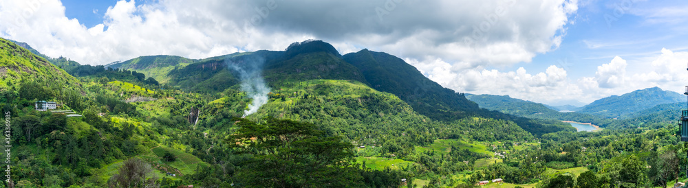 Panoramic landscape of Sri Lanka.  waterfall in the mountains and tea plantation. smoke behind trees.