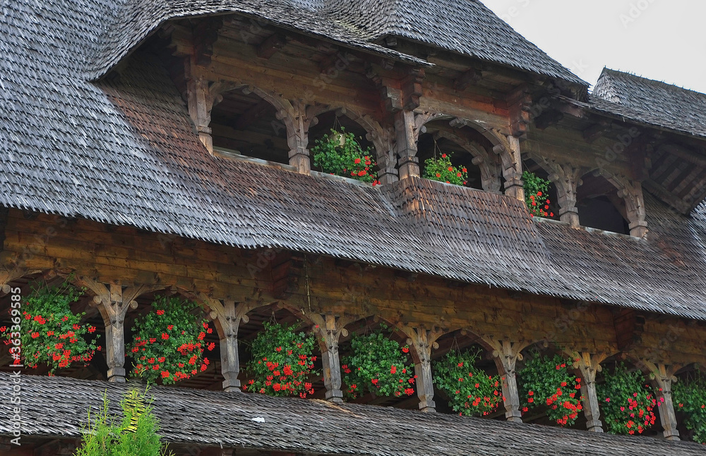 Barsana Monastery, Maramures, Romania, Europe, Summer 2018. Wooden building with red geraniums hanging from the windows of the Barsana Orthodox Monastery.