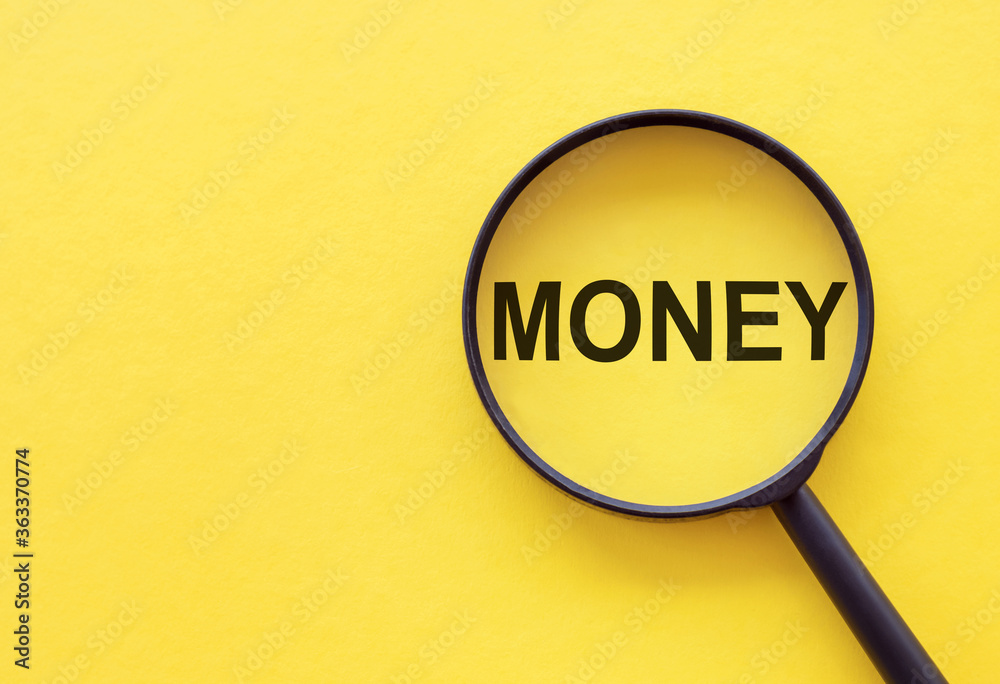 The word Money on magnifier glasses on yellow background The word Money on magnifier glasses on yellow background