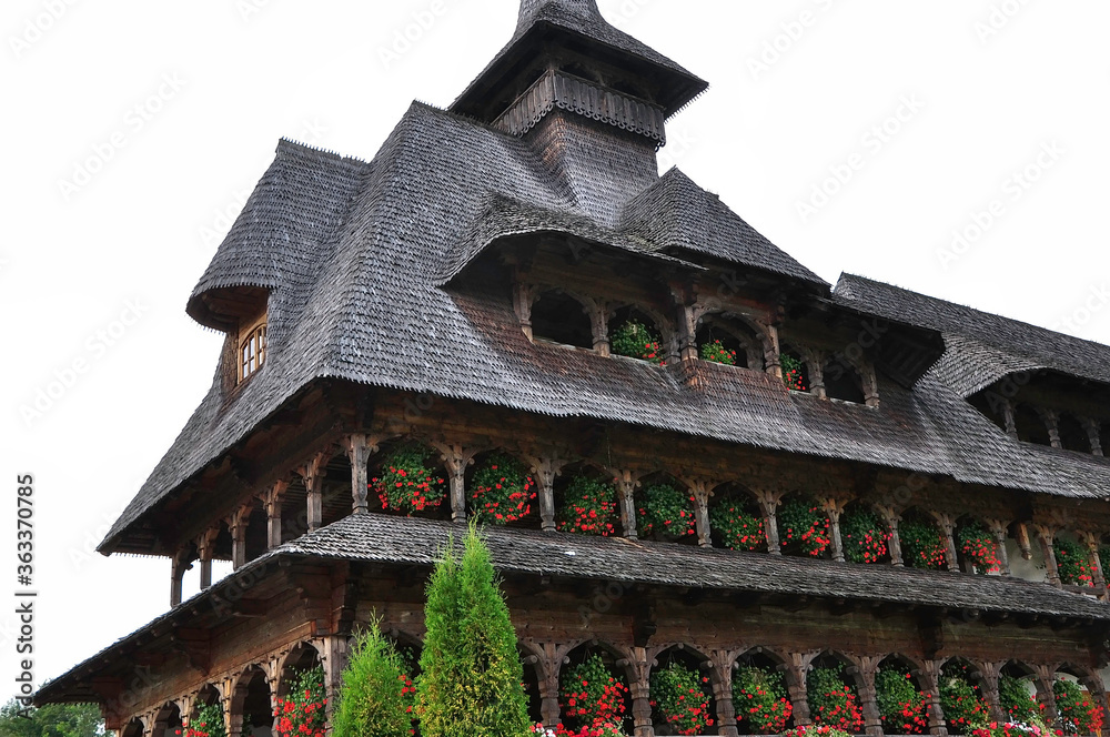 Barsana Monastery, Maramures, Romania, Europe, Summer 2018. Wooden building with red geraniums hanging from the windows of the Barsana Orthodox Monastery.