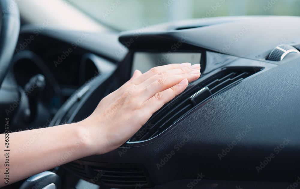Woman checks air conditioning in a car
