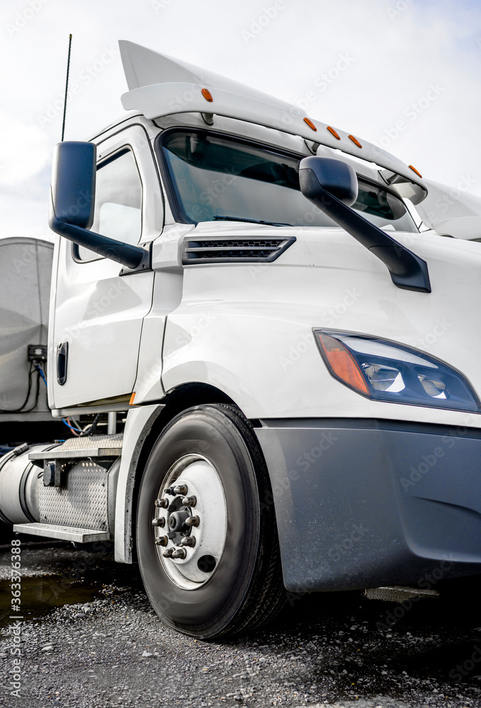 Φωτογραφία Big rig day cab white semi truck with roof spoiler and tank semi trailer standin