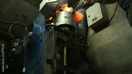 Molten silver being poured from a crucible into an ingot mold with the light coming from the molten silver. in the industrial workshop . the silver master photo