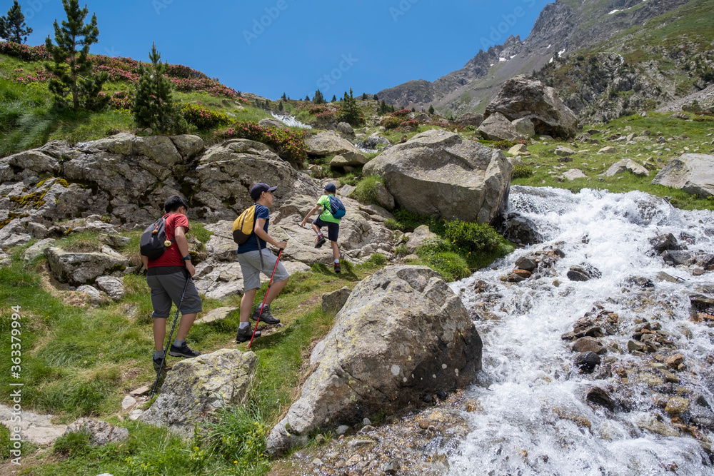 children climbing a mountain next to a river in the pyrenees