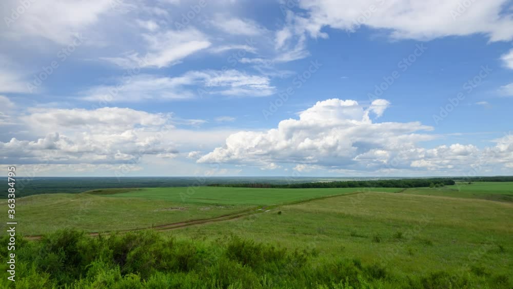 Timelapse of beautiful white clouds floating across the blue sky over green hills Timelapse of beautiful white clouds floating across the blue sky over green hills