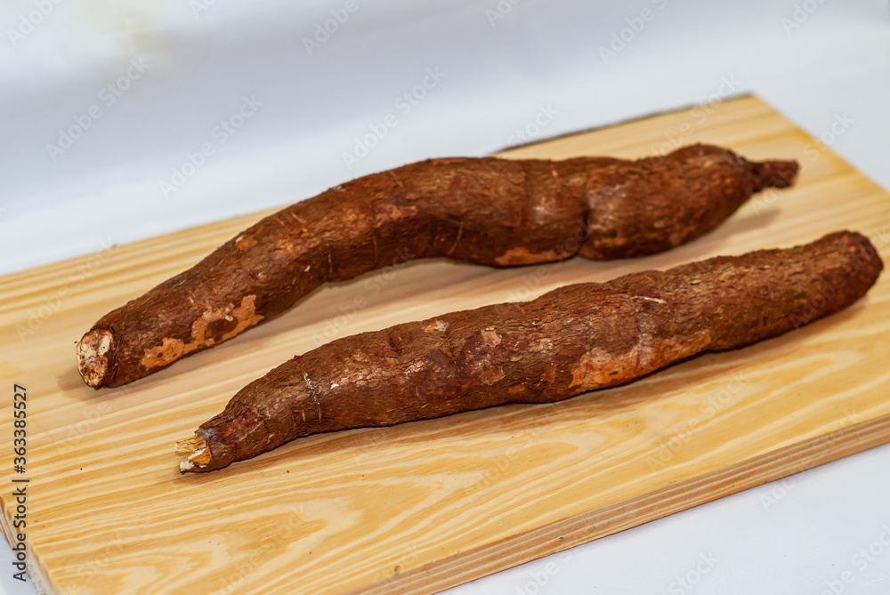Raw yucca on the wooden table, Manihot esculenta. (Cassava raw tuber). Cassava, also called mandioca, yuca, balinghoy, mogo, mandioca, kamoteng kahoy, tapioca and tapioca root. Focus selective.