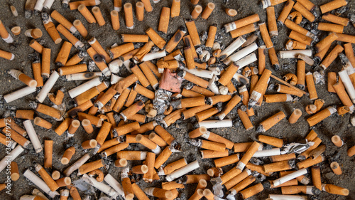 
Cigarette butts extinguished, in the sand, close-up