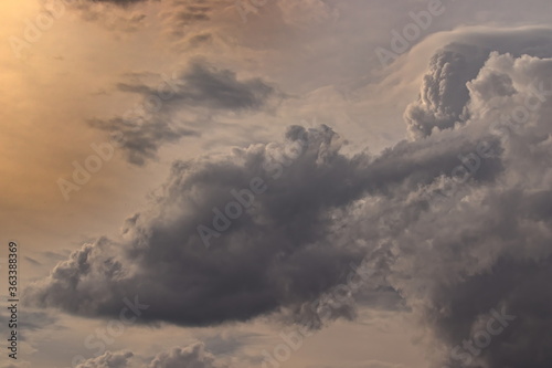 large gray cumulus clouds blown by the winds, floating across the dusk sky. © conpuli