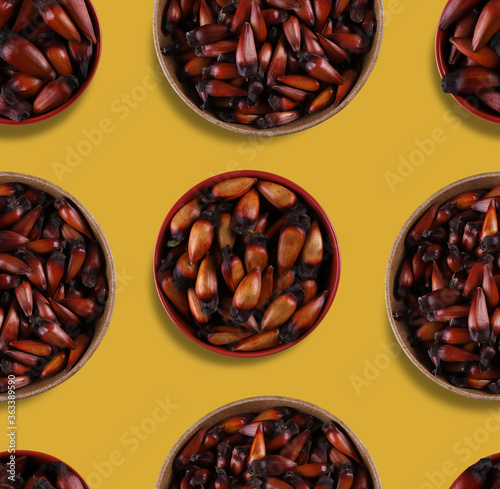 Pinion, traditional Brazilian food, Araucaria seed. Top view on yellow background. Continuous repeat pattern