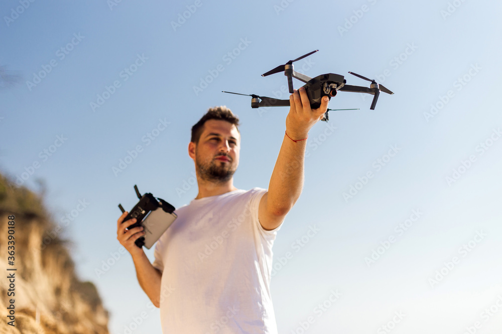 Young man holding drone before flight near ocean or sea. Pretty guy prepare  to pilot outdoor Photos | Adobe Stock