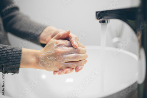 Young woman wash hands with soap in bathroom. Trendy coronavirus covid-19 concept