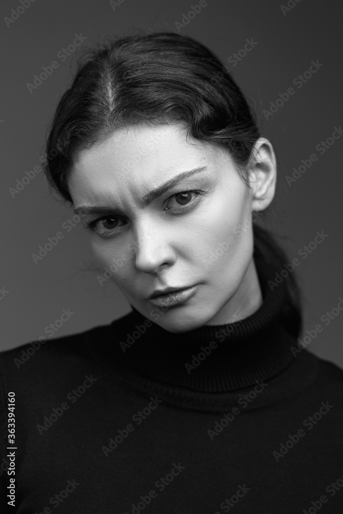 Attractive brunette girl in a dark sweater poses for the camera. black and white image