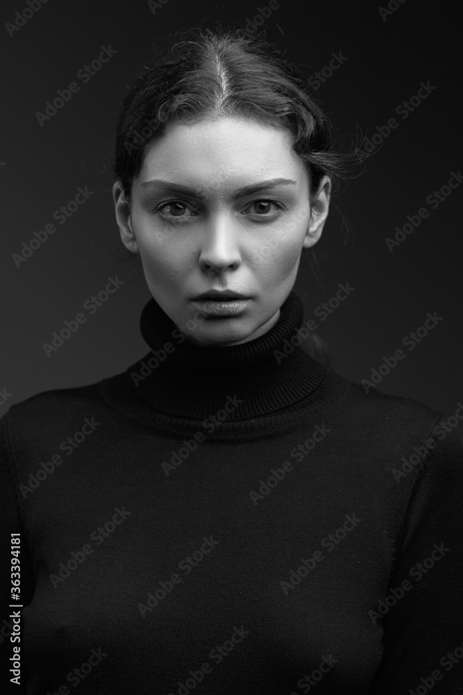 Attractive brunette girl in a dark sweater poses for the camera. black and white image Attractive brunette girl in a dark sweater poses for the camera. black and white image