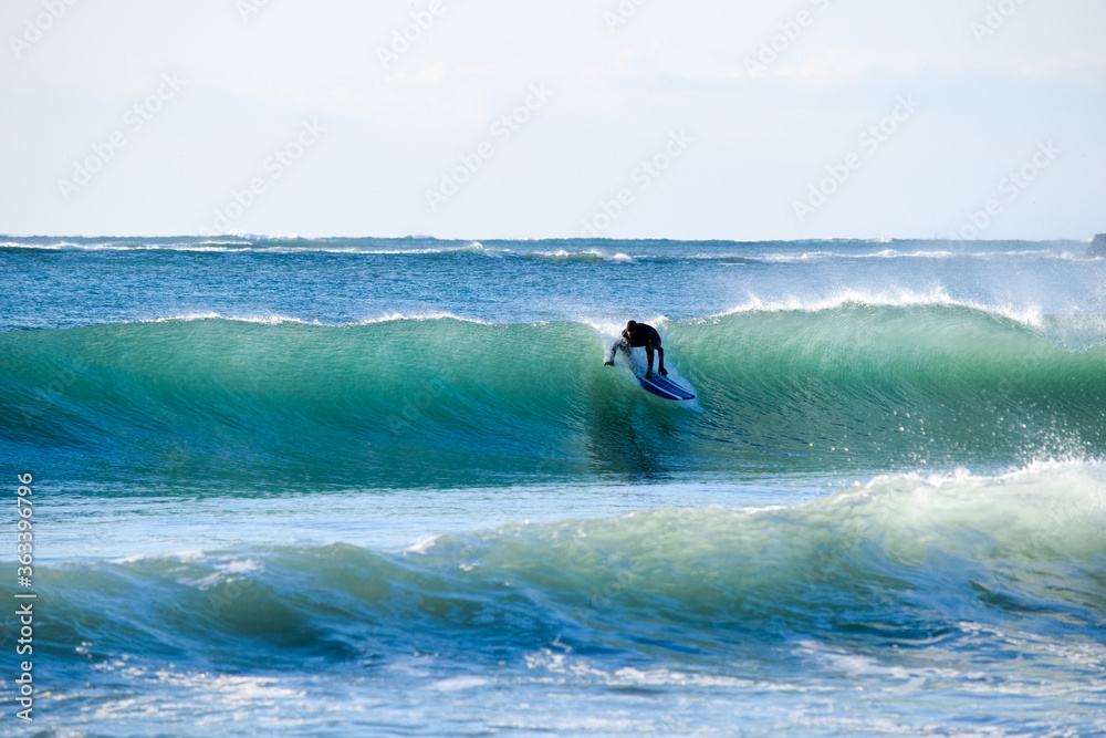 Surfer on Blue Ocean Wave riding on surfing board in Asia.  Japan is famous for its great waves near to Tokyo City