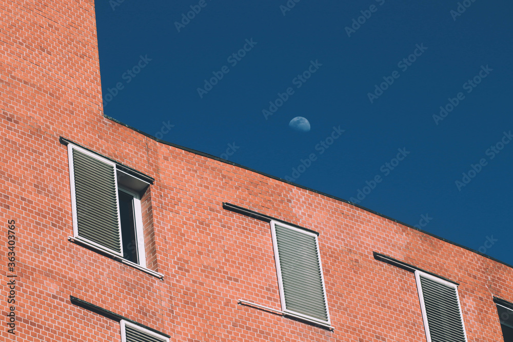 Luna catturata di giorno sopra ad una facciata di mattoni con canon EOS-200D 70-300mm.