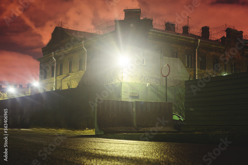 A night view of protected creepy penitentiary prison building facility, asylum exterior with barded wire on walls, red night sky, concept of scary house with maximum security photo