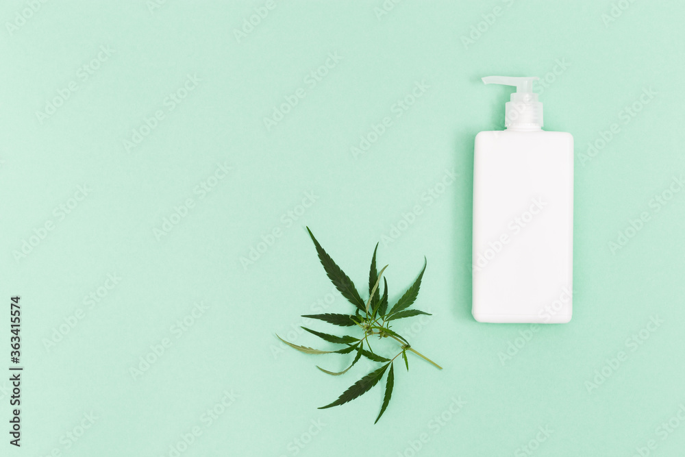 Jar with cosmetic product, gel or shampoo with cannabis oil on green colored background. White flack for self-care. View from above. Jar with cosmetic product, gel or shampoo with cannabis oil on green colored background. White flack for self-care. View from above.