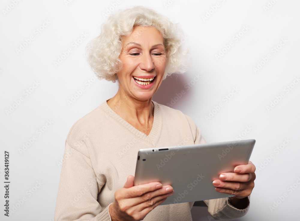 Happy mature woman using a tablet, communicates with children and grandchildren Happy mature woman using a tablet, communicates with children and grandchildren