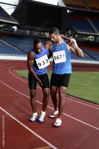 Male athlete helping another injured athlete