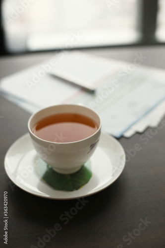 A cup of tea on the table, document and pen in the background