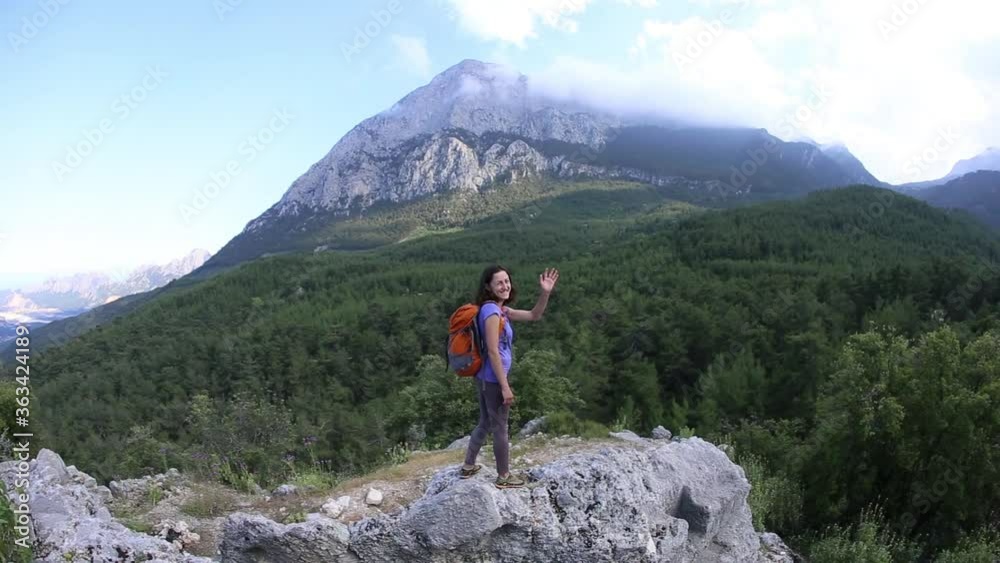 A woman with a backpack stands on top of a mountain and admires the beauty of a mountain valley, The girl travels to beautiful places, Reaching the goal. Beautiful landscape. A woman with a backpack stands on top of a mountain and admires the beauty of a mountain valley, The girl travels to beautiful places, Reaching the goal. Beautiful landscape.